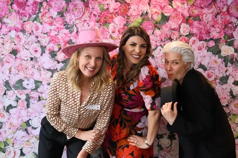 She Sharp members posing together at a pink floral photo wall during the 10-Year Anniversary celebration.