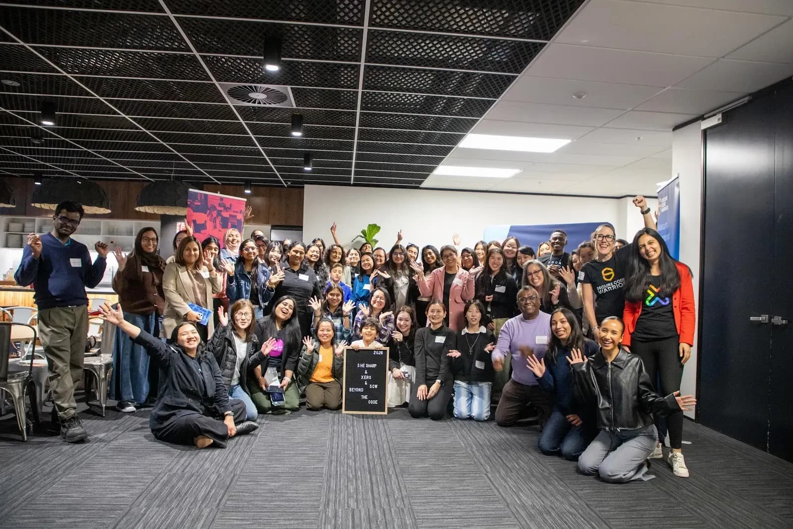 Attendees, speakers and the Xero and Secure Code Warrior teams gathered for a group photo at Xero's Parnell office, with a Beyond the Code letter board in front