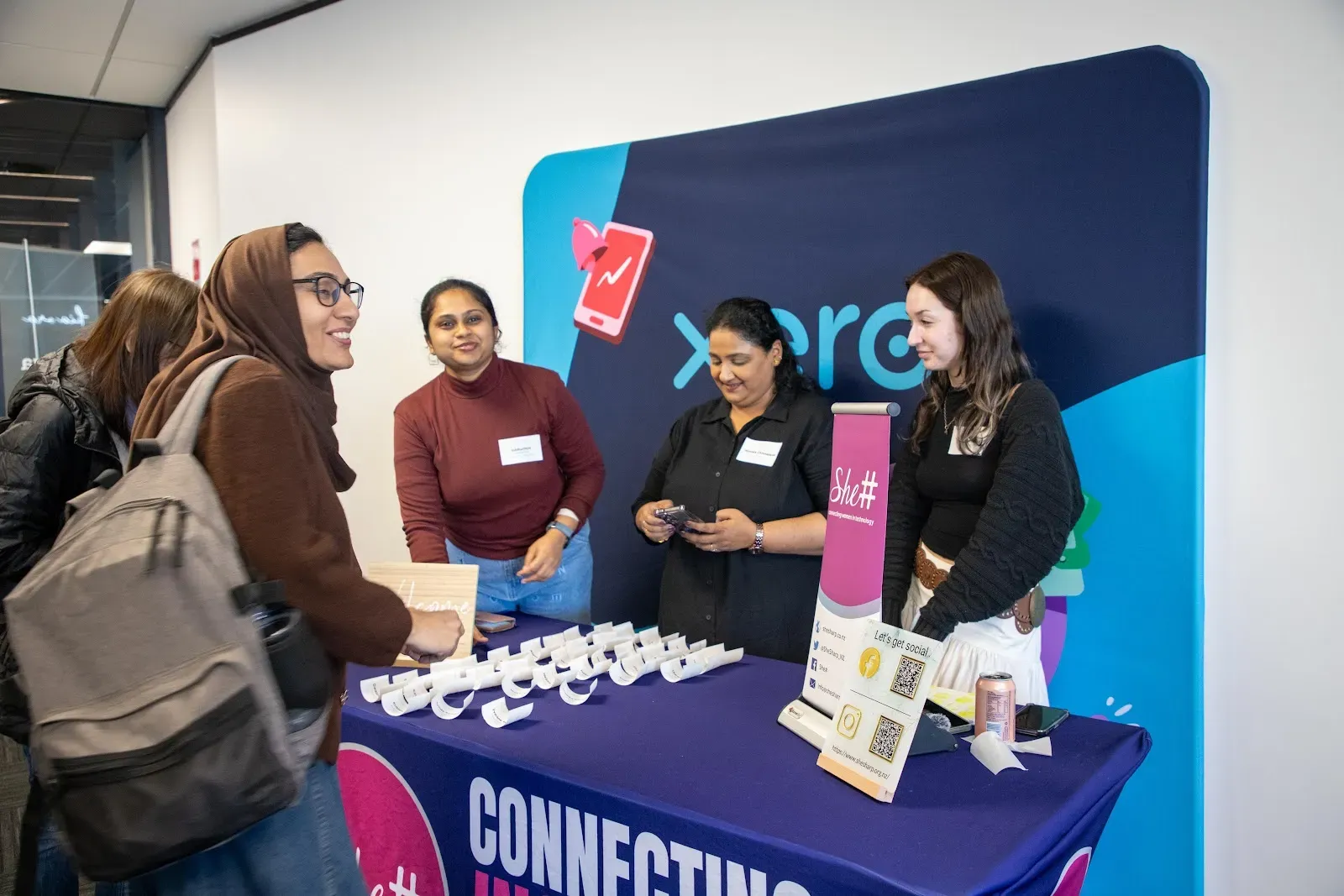 She Sharp volunteers welcoming arrivals at the registration table in front of a Xero backdrop