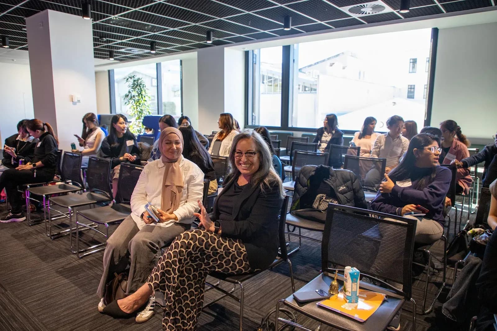 Attendees smiling from their seats as the room fills up before the session