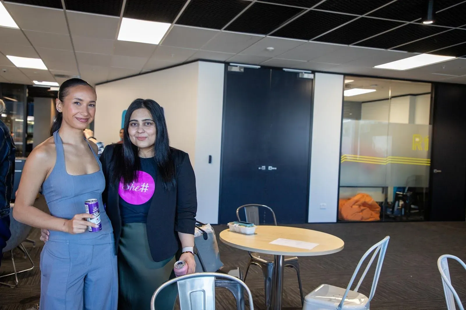 Two attendees posing together in the Xero office, one wearing a She Sharp t-shirt